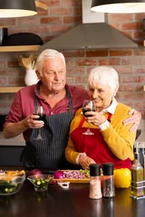  Happy caucasian senior couple preparing vegetables, drinking wine, embracing in kitchen, copy space © WavebreakMediaMicro