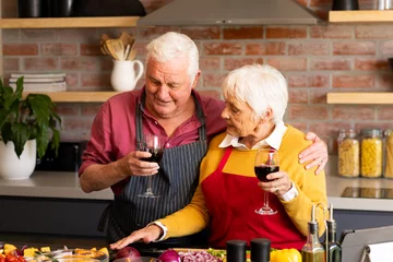  Happy caucasian senior couple preparing vegetables, drinking wine and embracing in kitchen © wavebreak3