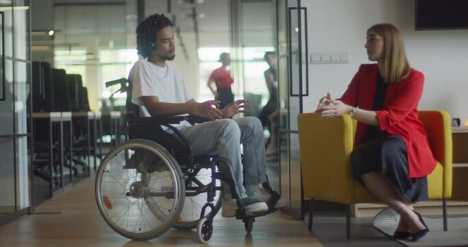 African American businessman in a wheelchair engages in a professional discussion with his colleague, addressing various business challenges and exploring solutions in an inclusive and diverse modern
