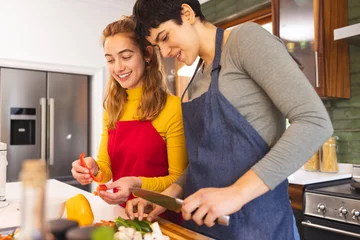  Happy biracial lesbian couple cooking, preparing vegetables in kitchen at home © wavebreak3