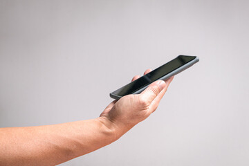 Man hand holding a phone, side view. On off white background, copy space.