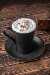 Hot chocolate in a black porcelain cup with a chocolate bar next to it