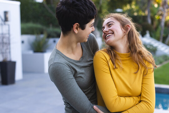 Happy biracial lesbian couple on garden terrace embracing and smiling at each other