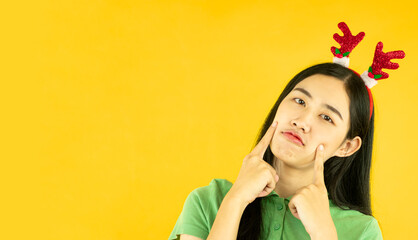 cute young asian woman wears a reindeer headband for christmas party isolated on yellow background