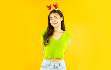 portrait of pretty asian woman wears a christmas reindeer headband isolated yellow background