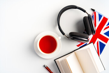 Notepad with British flag and headphones on white background. English language audio courses...