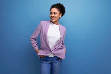 young well-groomed latin secretary woman with fluffy hair is dressed in a lilac jacket on a studio background with copy space