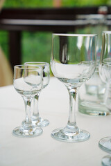 Empty wine glasses and shot glasses on a table with a white tablecloth.