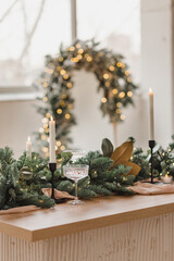 New Year's table decor from a Christmas tree, candles, garlands and other decorations. Stylish decor for home and living room. Christmas mood.