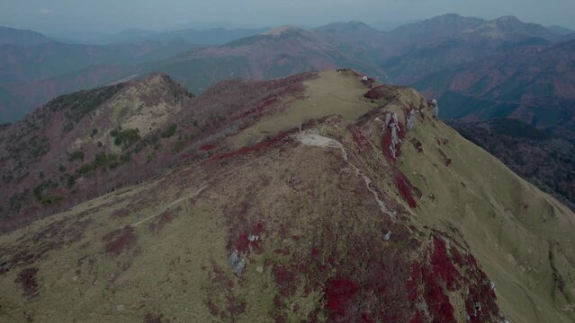 Drone flight over Mt Miune in Shikoku, Japan during Autumn. The mountains shows high contrast of green and red leaves.