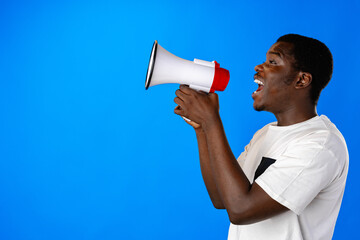 Positive african guy shouting with megaphone over blue background