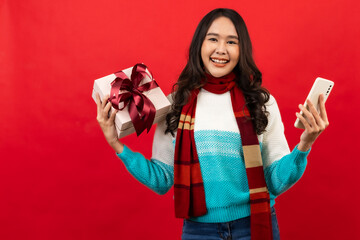 ..Happy smiling asian woman holding gift box over red ..Happy smiling asian woman holding gift box over red background...