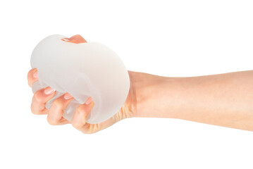 Female hand squeezing soft round breast implant on white background. Plastic surgery. 