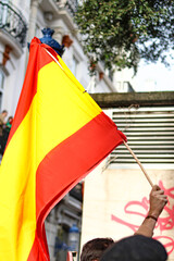 A hand holding the flag of Spain during a demonstration
