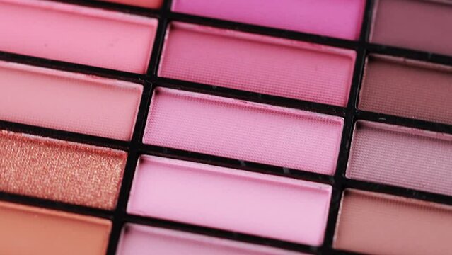 Background of multi-colored eye shadows for applying makeup on the eyelids. Modern cosmetics, macro, rotation