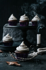 Cute chocolate ghost cupcakes on dark table for Halloween.