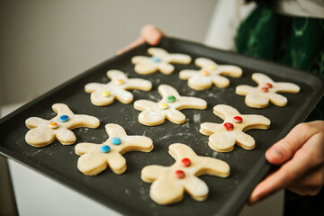 Front view of a woman showing her decorated gingerbread on sheet
