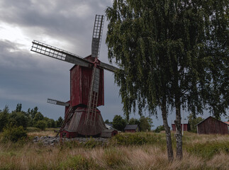 Old red wooden windmill, old red huts in the field