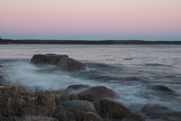 pink sunset on the stone shore and the raging sea