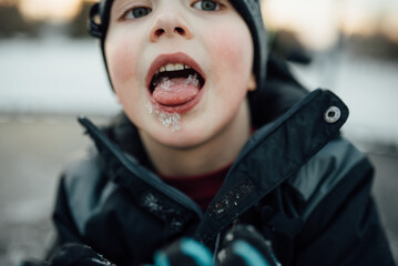 Close up of boy outside in winter wearing warm gear with tongue