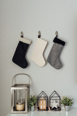 Styled shot of 3 stockings hung on a wall over Christmas decorat