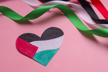 The heart shape paper represent the Palestinian flag and colorful ribbons on pink background