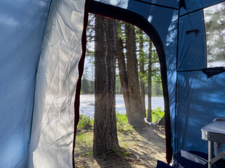 View from the tent to the mountain river in a beautiful place for camping in a coniferous forest. . High quality photo