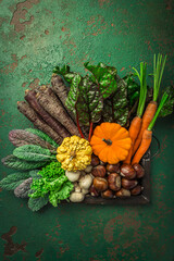 Organic raw autumn and winter vegetables on kitchen table with carrots, chesnuts, chard, kale