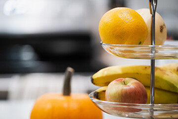 Orange, banana, apple and pear on a fruit tray arrangement on kitchen arrangement next to a pumpkin. Kitchen and food styling. Easy access to heavy fruits. Kitchen aesthetics.