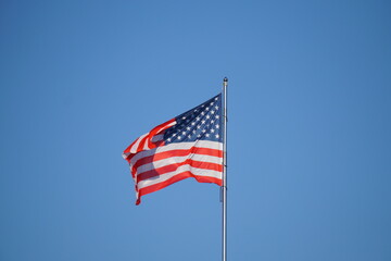 American Flag . USA national flag waving on wind against blue sky. Slow motion