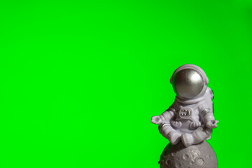 Plastic toy astronaut on green chroma key background Template Mock up Copy space. Concept of out of earth travel, private spaceman commercial flights. Space missions and Sustainability