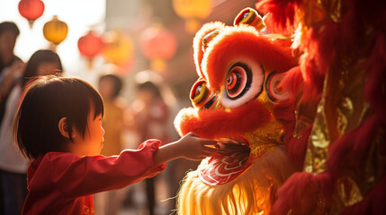 Baby boy child in traditional red Chinese costume celebrating Chinese New Year with Chinese lion dance.