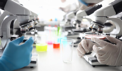 Male hand in protective latex gloves. Many microscopes in forensic science laboratory closeup backgroung. Sale of specialized equipment and chemicals concept