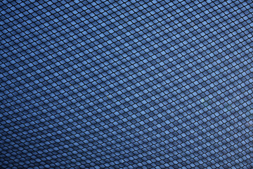 grid Fence with Sky on Background. cage net metal net on blue backdrop.