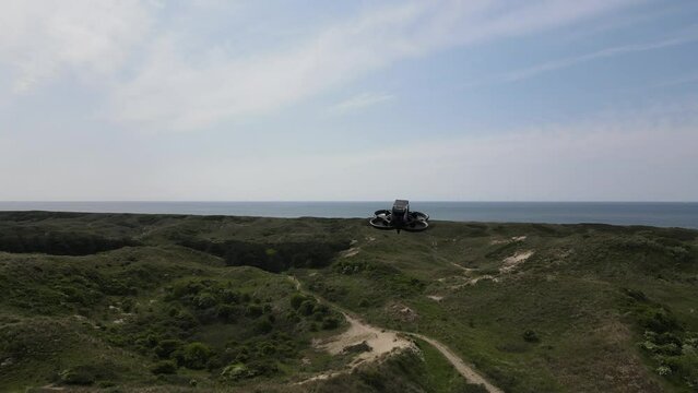 Tiny FPV drone hovers in green nature landscape, Dunes of Schoorl, Netherlands