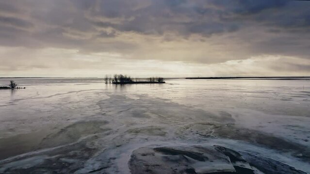 A drone shot flying towards island in the middle of lake Eire which is fronzen.