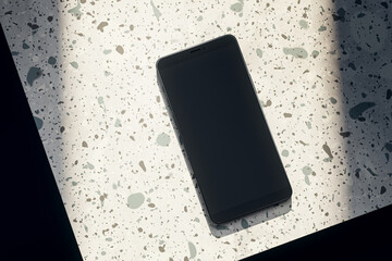 Top view of empty black smartphone on spotted table. Mock up, 3D Rendering.