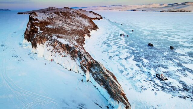 Ogoy island in winter Baikal lake, Siberia, Russia. Aerial view. Tourists walking around the island. Cars and hovercrafts ride on the ice. Winter landscape
