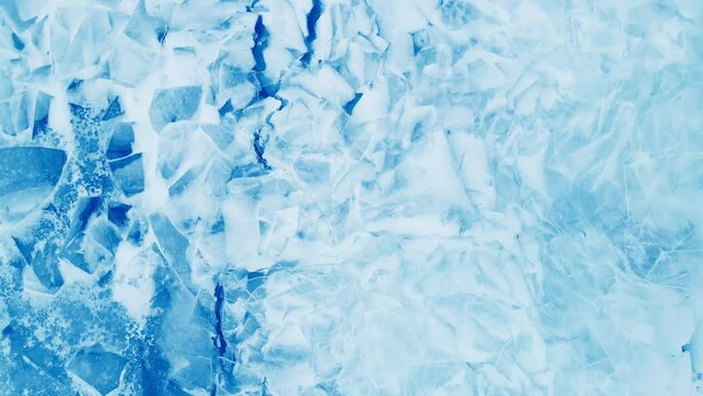 Blue ice with snow on the frozen lake in winter. Aerial top down view. Abstract winter nature background
