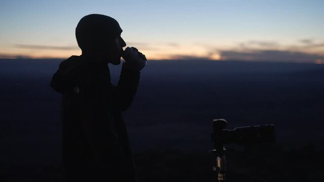 Young astro photographer takes photos after sunset while sipping on a beverage