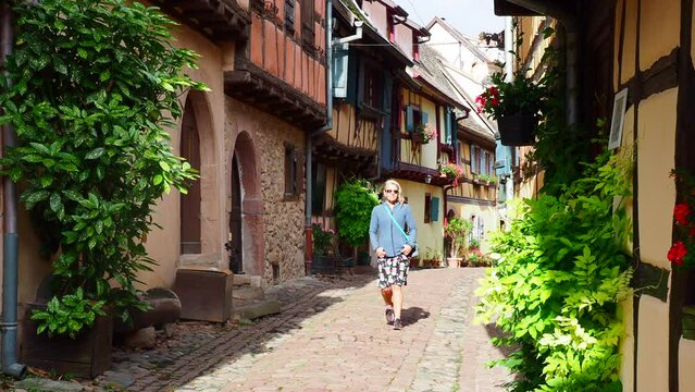 Woman walking through the Beautiful Streets in the village Equisheim Alsace France