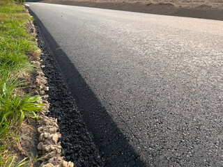 A close-up view of the hot and fresh asphalt layer on a newly constructed road, showing the texture...