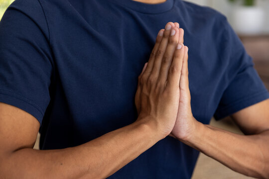 Midsection of biracial man doing yoga and meditating at home - Powered by Adobe