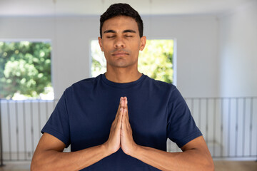 Biracial man doing yoga and meditating at home