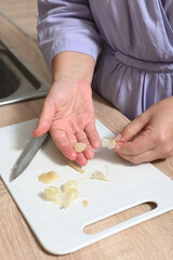 Woman in the kitchen cleans and cuts pickled garlic on a cutting board.