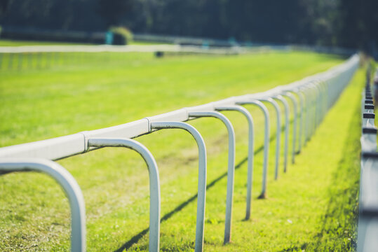 Empty horse race track with green grass and white fence