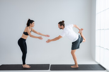 Young couple practicing yoga in a white room of studio.