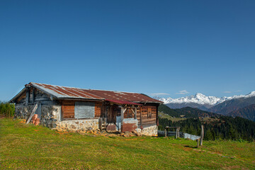 Obraz premium Highland houses made of stone and wood. Wooden plateau houses built on the hill. Historical highland houses. Sal Plateau Rize. Wooden plateau houses in Turkey. Sal Plateau Rize Türkiye. 