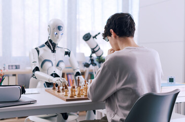 Concentrated chess game between boy and robot