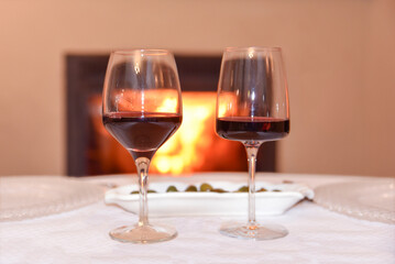 Two glasses of wine near cozy fireplace in country house